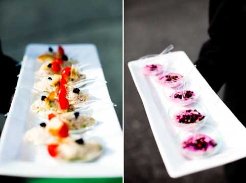 Close-up detail shot of wedding canapés during what appears to be a cocktail hour. The left image shows a long white rectangular platter holding a row of individual spoons topped with light-colored mousse or tartare garnished with red and yellow pepper pieces and black caviar or olive pearls. The right image shows a similar white rectangular platter being held by a person in dark clothing, carrying small clear cups or shot glasses filled with a bright pink cream or mousse topped with black caviar or berry garnish. Both platters suggest a modern, refined catering presentation with a color palette of white, pink, red, and black.