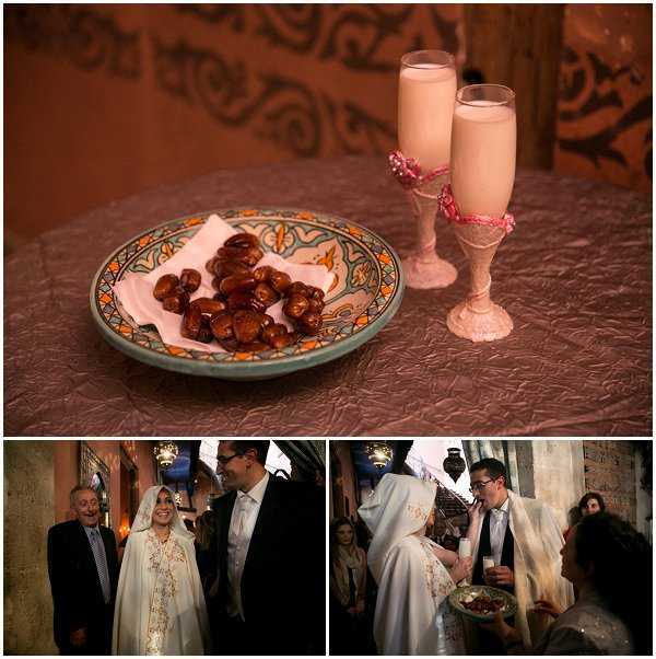 A three-image collage documenting an indoor Moroccan-style wedding ceremony and reception. The top image is a close-up detail shot of a traditional ceramic plate with orange and blue geometric patterns holding dates on a pink tissue, alongside two pink milk-filled flute glasses decorated with pink ribbon and lace wrapping, set on a mauve embossed tablecloth against a carved terracotta wall — these are traditional North African wedding ceremony elements. The bottom-left image shows the bride and groom with an older male guest in an indoor stone-walled venue; the bride wears a white hooded kaftan-style cape with gold embroidery and a white veil, while the groom wears a white dress shirt and tie. The bottom-right image shows the bride receiving or tasting food from a plate held by a female guest, with several other guests visible in the background, capturing an interactive ceremonial moment consistent with a traditional Moroccan or North African wedding ritual.