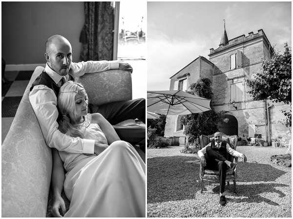 A black-and-white diptych featuring two portrait shots from the same wedding. On the left, the bride and groom are seated together on an ornate upholstered sofa indoors, with the bride reclining against the groom's chest; she wears a fitted white dress with a high neckline and a delicate hair accessory, while the groom wears a white shirt, dark waistcoat, and tie. The composition is a close-mid portrait with soft natural light from a nearby window. On the right, the groom sits alone in an antique armchair placed on a gravel courtyard in front of a French chateau-style building with a pointed turret and shuttered windows, with a large patio umbrella visible behind him; the shot is a wide portrait capturing both the subject and the architecture. Both images have strong contrast with deep blacks and bright highlights. Potential venue feature image.