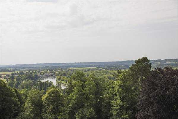 Wide landscape shot taken from an elevated vantage point, showing a sweeping view over treetops toward a river and open countryside beyond. No people, wedding details, or decor are visible in the frame. The image appears to be a venue grounds or location establishing shot, though no buildings or architectural features are shown. Potential venue feature image.