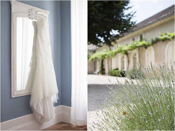 A two-image composite showing getting-ready details alongside a venue exterior shot. On the left, an ivory strapless lace wedding gown with a layered tulle skirt hangs from an ornate white-framed mirror against a pale blue wall, with sheer white curtains in the background — a close-up detail shot. On the right, a softly focused exterior view of a French-style venue with white rendered arched colonnades, vine-covered walls, and a gravel courtyard, with lavender plants in the foreground — a medium wide shot. Potential venue feature image.