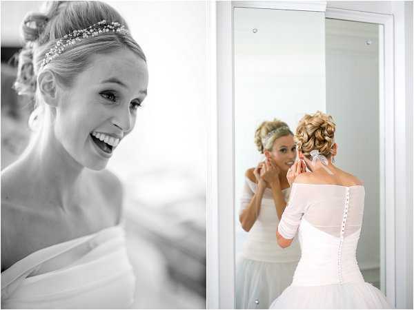 A two-image composite from the bride's getting-ready moments. The left image is black-and-white, showing a close-up portrait of the bride laughing, wearing a delicate crystal and pearl bridal headband and an upswept hairstyle, with soft contrast and bright highlights. The right image is in color, showing the bride standing in front of a full-length mirror in a white room, putting on an earring; she is wearing an off-the-shoulder white gown with three-quarter-length sleeves, a corseted back with button detailing, and the same crystal headband, with her blonde hair in a chignon updo. Both shots are portrait-style and capture solo getting-ready preparation indoors.