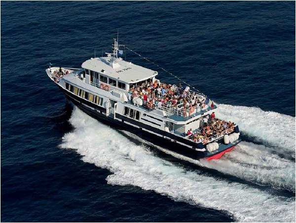 This image does not appear to show a wedding photograph. It is an aerial shot of a large passenger ferry or excursion boat traveling at speed across open water, with a large crowd of people visible on the upper and lower open decks. There are no visible wedding-related elements such as bridal attire, ceremony decor, or reception setup. This image does not belong in a wedding content library.
