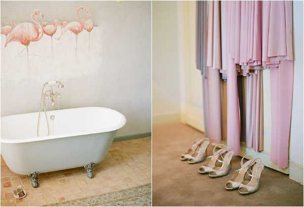 A two-image composite showing getting-ready details from a wedding. The left image features a white clawfoot freestanding bathtub in a room with terracotta tile flooring and a decorative wall mural depicting pink flamingos, with antique-style chrome faucet fittings. The right image shows a rack of bridesmaid dresses in a mix of blush pink, mauve, and lilac floor-length gowns, with three pairs of nude/champagne strappy heels arranged on the floor below them. Both images are close-up detail shots with a soft, warm color palette and a romantic, feminine styling theme.