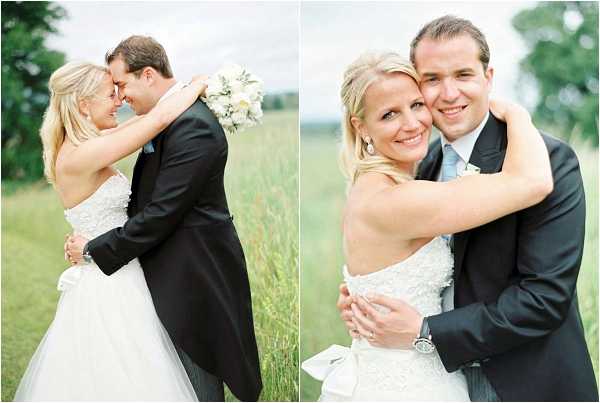 A couple portrait diptych taken outdoors in an open field with tall green grass. The bride wears a strapless white lace and tulle ballgown with a large white satin bow at the back, and carries a white and ivory bouquet. The groom wears a dark charcoal suit with a pale blue tie and a white boutonnière. In the left image, the couple leans foreheads together in a close romantic pose, captured as a mid-length shot. In the right image, the bride hugs the groom from behind and smiles directly at the camera in a closer portrait crop. The overall styling is classic and clean with a white and pale blue color palette.