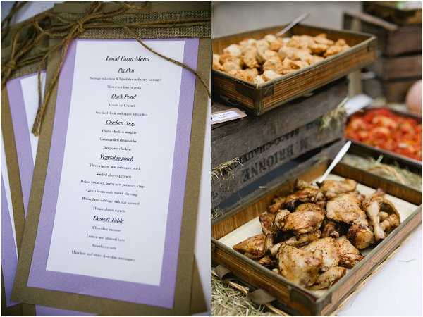 A side-by-side detail shot of a rustic wedding reception's food and stationery. On the left, printed menu cards with a lavender and kraft brown border, tied with twine, display a 'Local Farm Menu' with sections including Pig Pen, Duck Pond, Chicken Coop, Vegetable Patch, and Dessert Table. On the right, a buffet station is set up with wooden crates lined with hay, holding roasted chicken pieces, bread rolls or pastries, and what appears to be a tomato salad, reflecting a farm-to-table rustic styling theme.