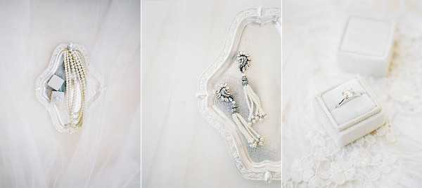 A three-panel flat lay detail shot of bridal accessories arranged on and around an ornate white decorative tray, placed on what appears to be ivory lace or tulle fabric. The left panel shows a multi-strand pearl bracelet with a small crystal or diamanté clasp. The center panel displays a pair of drop earrings featuring crystal and silver tassel detailing with pearl accents. The right panel shows a solitaire diamond engagement ring presented in an ivory velvet ring box with gold trim. The overall palette is white and ivory with silver accents, suggesting a classic and refined bridal styling theme.