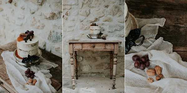 A styled flat-lay and detail triptych showcasing a rustic wedding cake display against a raw stone wall. The left panel shows a close-up of a small semi-naked cake topped with red grapes, dried apricots, and dark berries, placed on a glass cake stand atop a draped ivory linen cloth with additional grapes and cork accents. The center panel shows the same cake displayed on a weathered antique wooden side table with turned legs, giving context to the full styled vignette. The right panel is a detail shot of the ivory linen cloth styled with red grapes, whole walnuts, and a dark dried element, adding to the autumnal harvest aesthetic. The overall styling palette is warm and earthy — ivory, warm wood tones, dusty red, and muted gold — with a rustic, organic theme.
