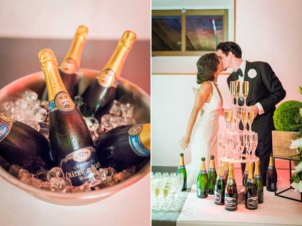A split image combining two shots from what appears to be a wedding reception held indoors. The left panel is a close-up detail shot of multiple bottles of Château de Blice champagne chilling in a pink bowl filled with ice. The right panel shows the couple sharing a kiss behind a champagne tower made of stacked coupe glasses, with several champagne bottles arranged on the table in front of it; the groom wears a classic black tuxedo with a bow tie and white boutonniere, and the bride wears a strapless white gown. The setting is a bright indoor reception space with a warm, modern styling approach, and the champagne service is clearly a focal feature of the celebration.