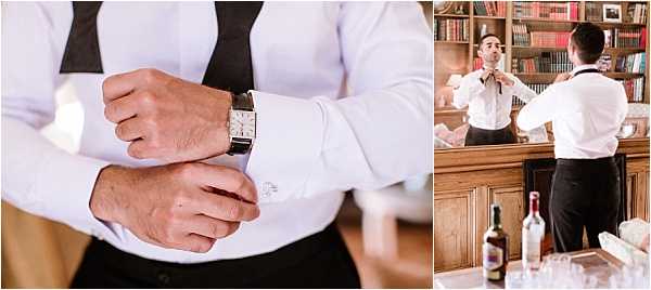 A two-panel getting-ready image featuring the groom preparing before the ceremony. The left panel is a close-up detail shot of the groom adjusting his cufflinks and watch — a rectangular-faced dress watch with a dark leather strap — while wearing a white dress shirt and black trousers with suspenders visible. The right panel shows the groom from behind in a medium shot, adjusting his black bow tie while looking into a mirror above a wooden bar cabinet stocked with books, wine bottles, and glassware, suggesting a chateau or manor house interior. The overall styling is classic black-and-white formal attire.
