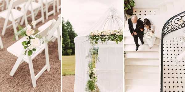 A triptych of three wedding images from what appears to be the same event. Left panel: a close-up detail shot of white folding ceremony chairs arranged in rows outdoors, with aisle chairs decorated with small posies of blush pink roses and green foliage tied with white ribbon. Center panel: a mid-shot of a white ceremony arch or birdcage-style structure draped with sheer white fabric and adorned with a garland of cream and blush florals with trailing greenery, set against an outdoor garden backdrop; the overall decor palette is white and soft blush with lush green foliage in a classic, romantic style. Right panel: an aerial overhead shot looking down a curved white staircase with black wrought-iron railing and black-and-white tiled floor, showing a bride in a short white dress being escorted by a man in a dark suit, likely a father-daughter moment before the ceremony.