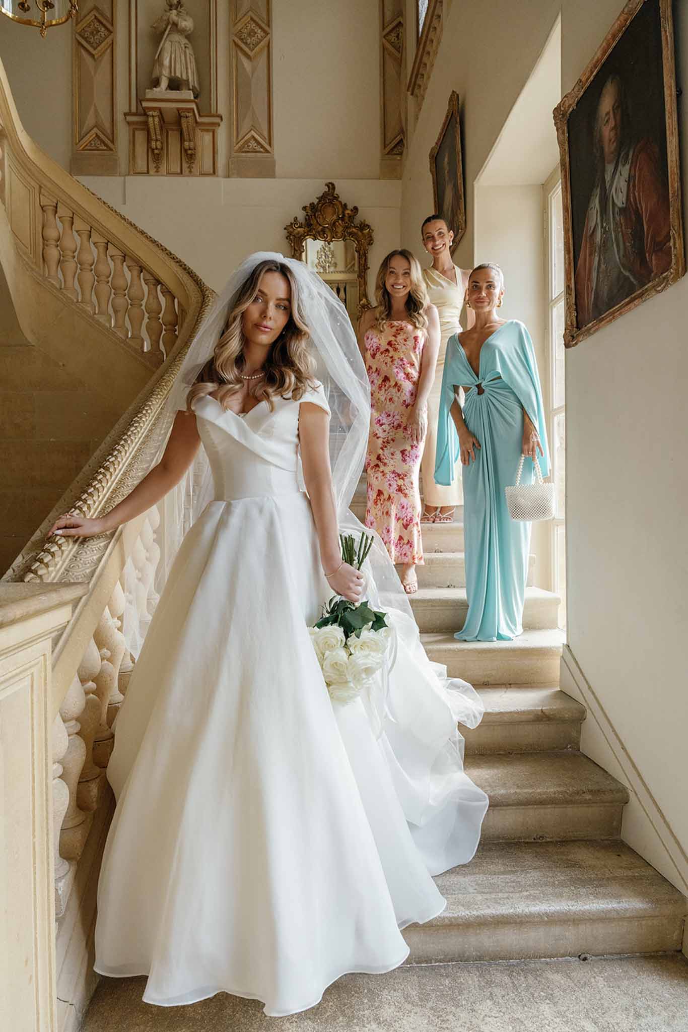Bride and bridal party on grand staircase in classical mansion interior