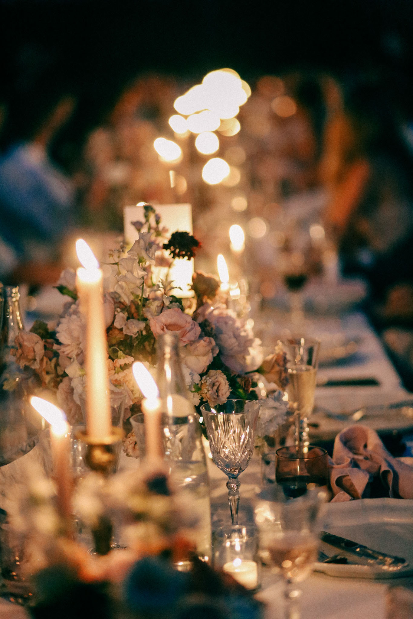 Candlelit reception table with blush pink roses, lavender blooms, gold candlesticks, and crystal glasses