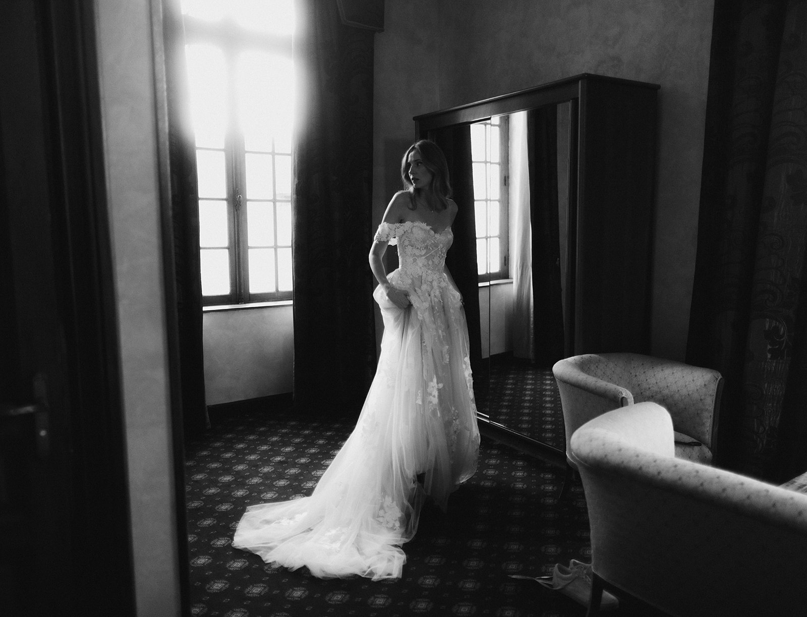 Black and white bride in floral applique gown with tulle skirt silhouetted against window light