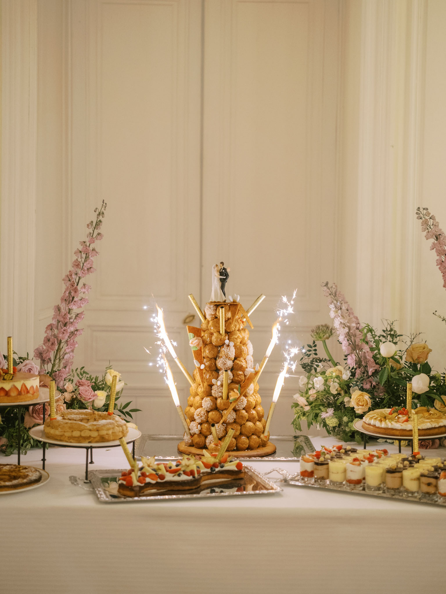 French dessert table with croquembouche, sparklers, pastries, and pink floral arrangements at chateau reception