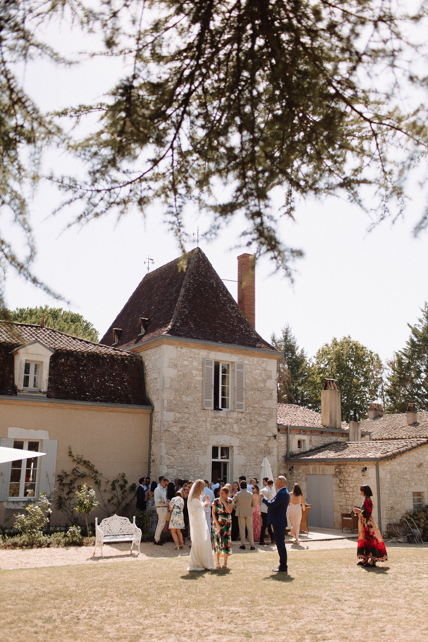 Wedding guests mingling in the courtyard of a French stone manor house during outdoor cocktail hour