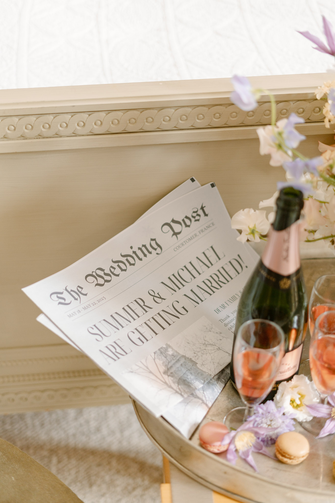 Welcome tray with Wedding Post newspaper, rose champagne, macarons, and lavender blooms