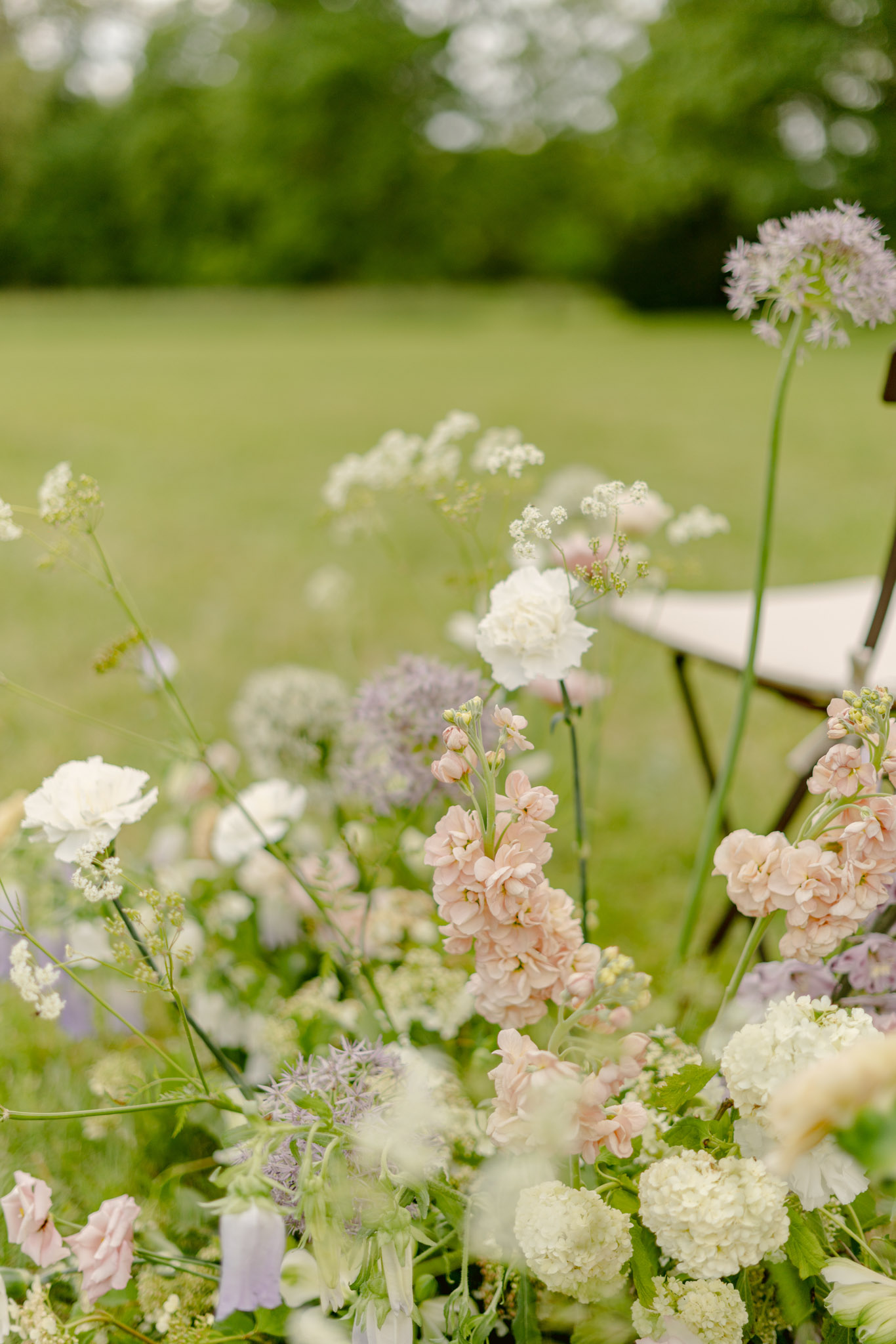 Wildflower aisle arrangement of blush stock, white lisianthus, lavender alliums, and blue eryngium