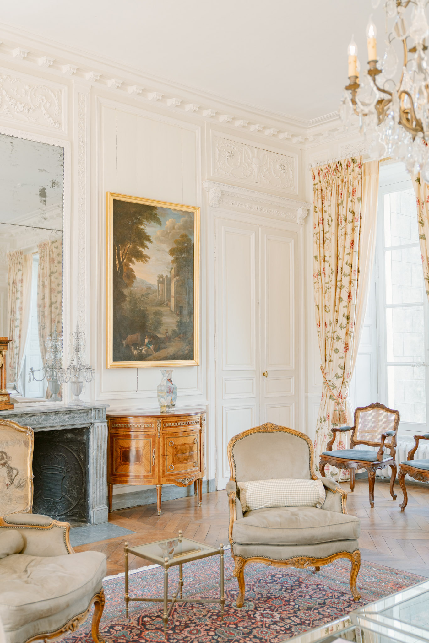 Chateau salon with boiserie paneling marble fireplace sage velvet armchairs and crystal chandelier