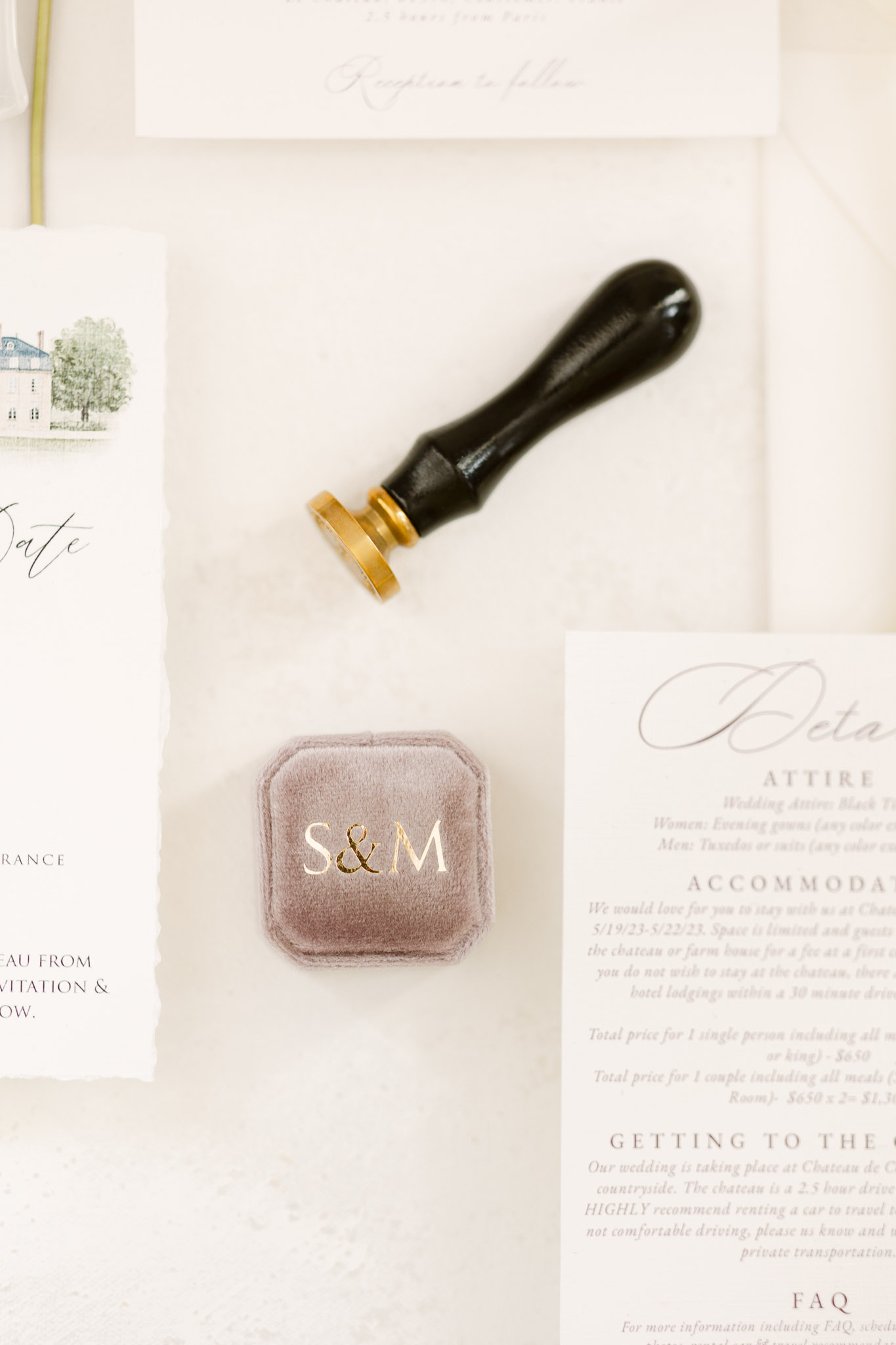 Stationery flat lay with calligraphy invitation wax seal stamp watercolor chateau card and dusty mauve velvet ring box