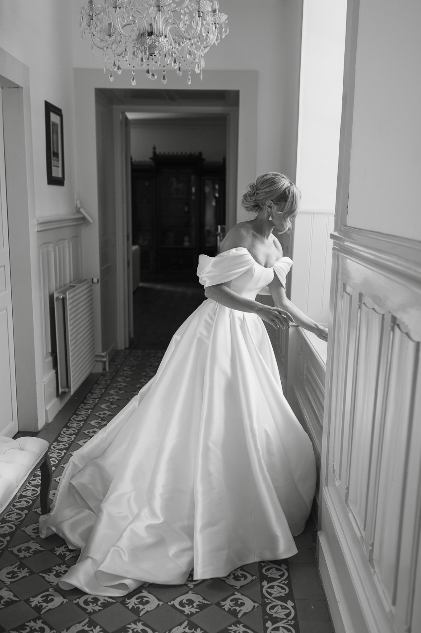 Black and white bride from behind in satin ballgown on patterned tile floor in chateau hallway