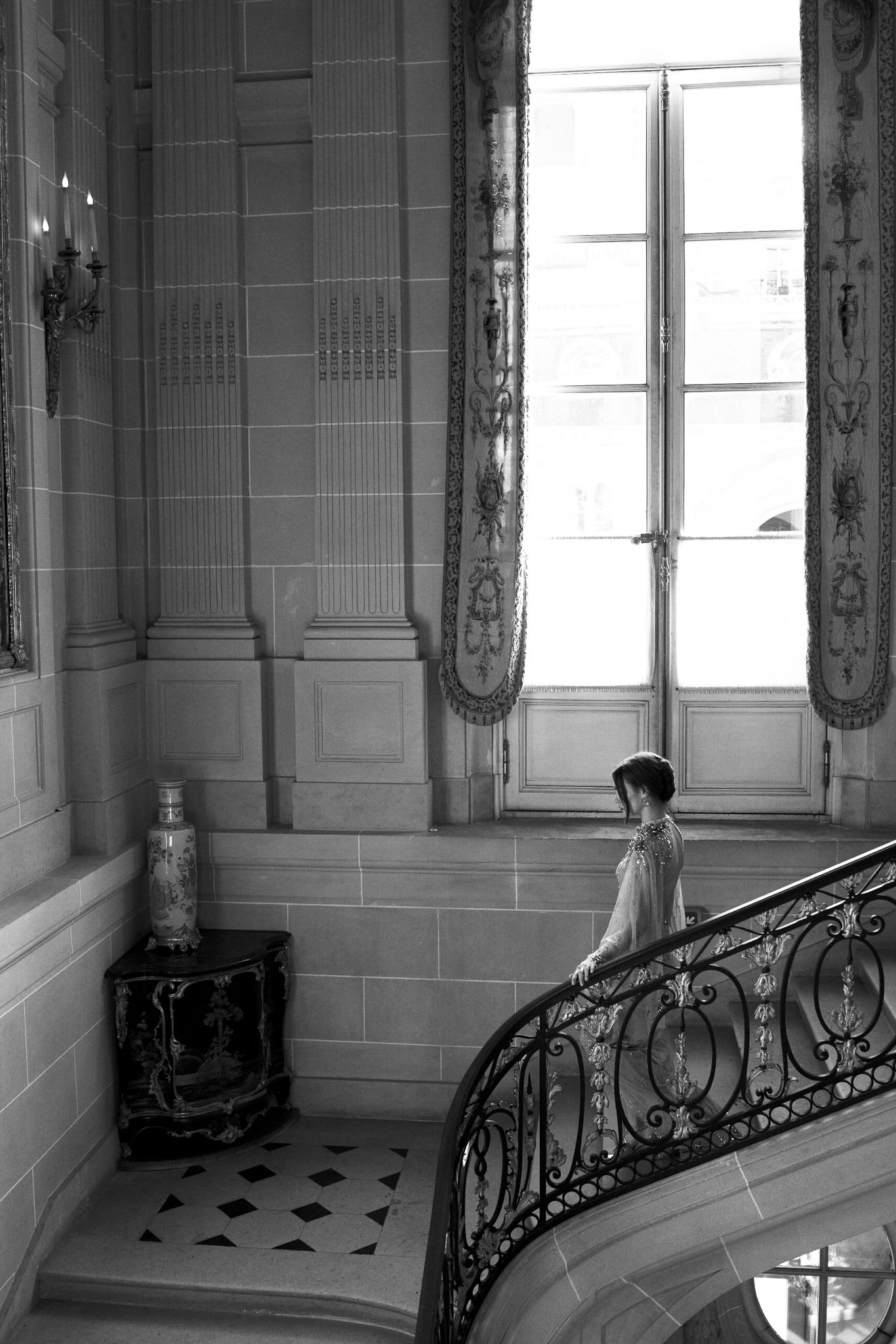 Black and white bridal portrait on a grand staircase landing with classical French architecture and natural window light