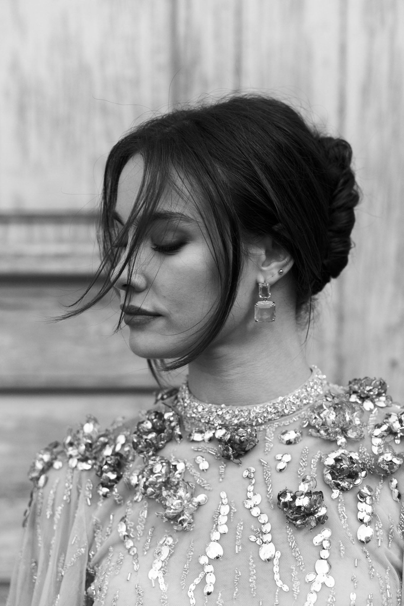 Close-up of bride with eyes closed wearing sequined floral cape and drop earrings in B&W