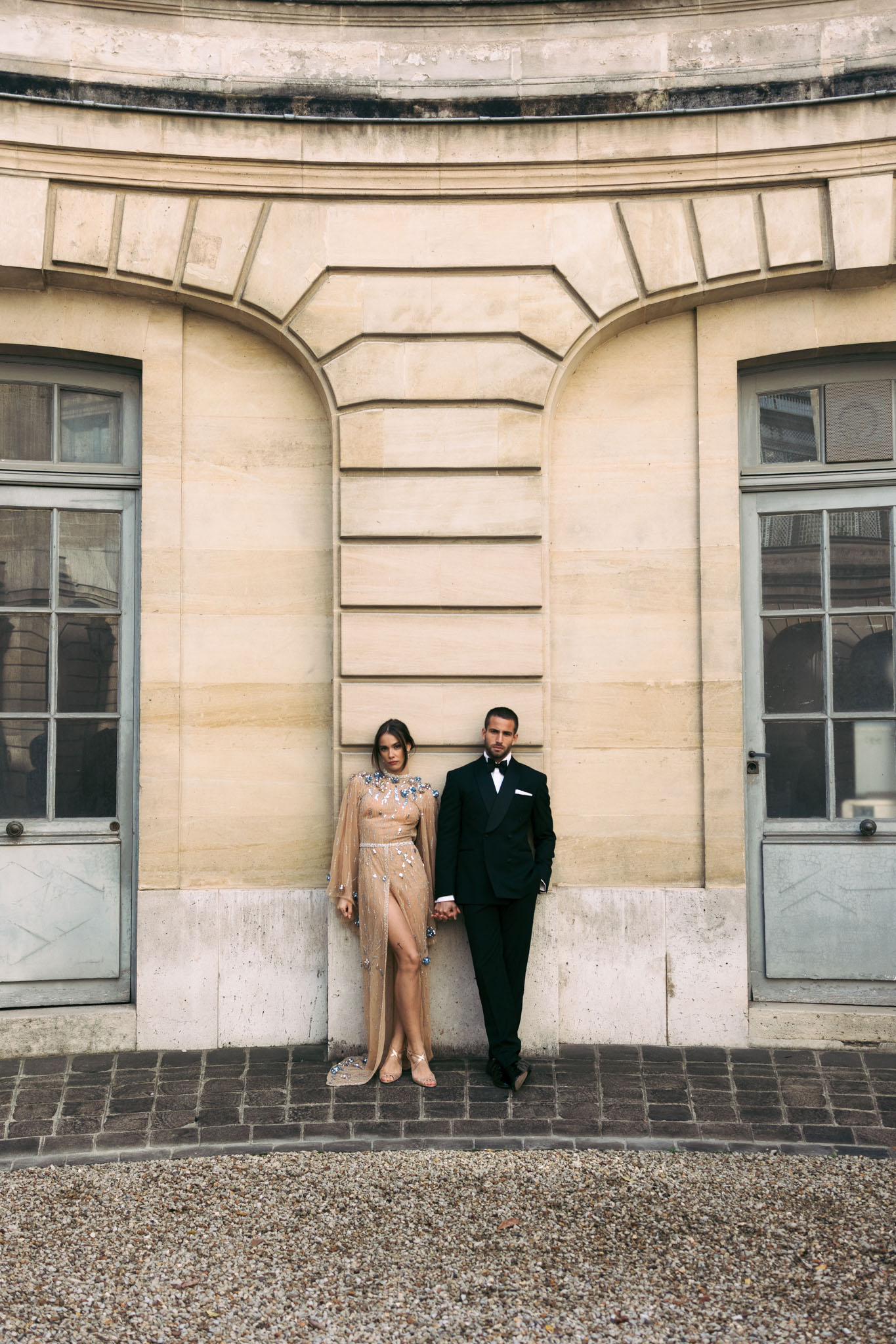Couple in formal pose against classical limestone building with arched detailing