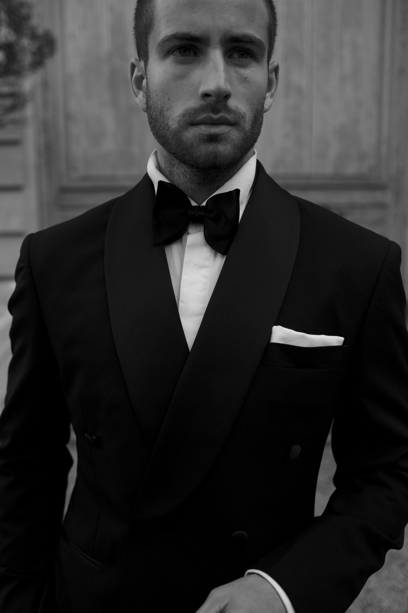 Black-and-white portrait of groom in double-breasted tuxedo with shawl lapel and white pocket square