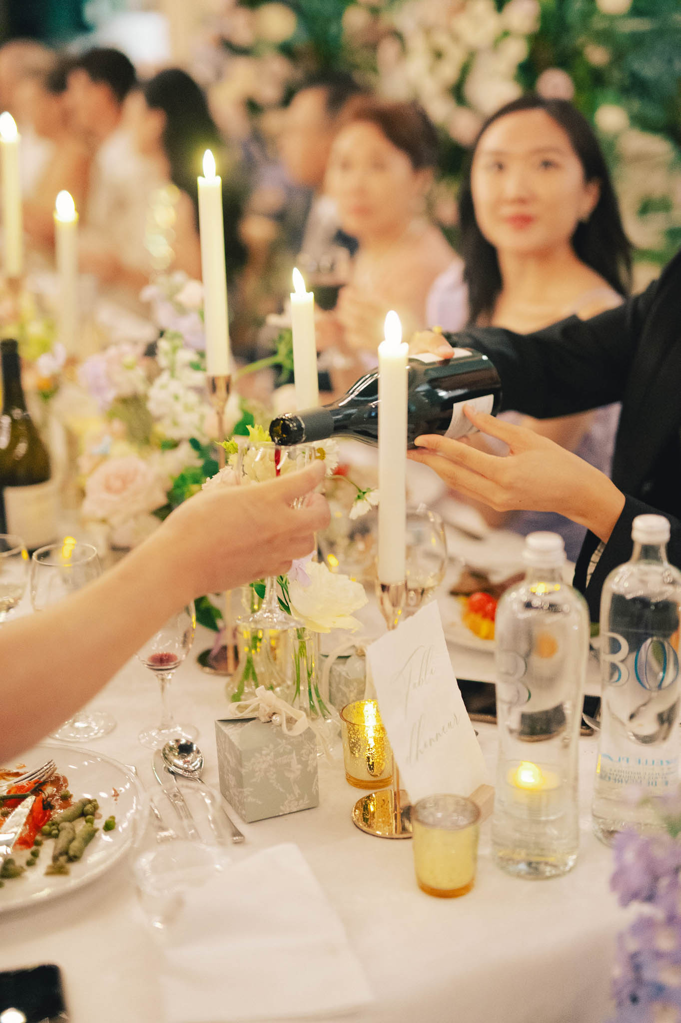Indoor reception table with blush roses, white ranunculus, gold votives, and taper candles