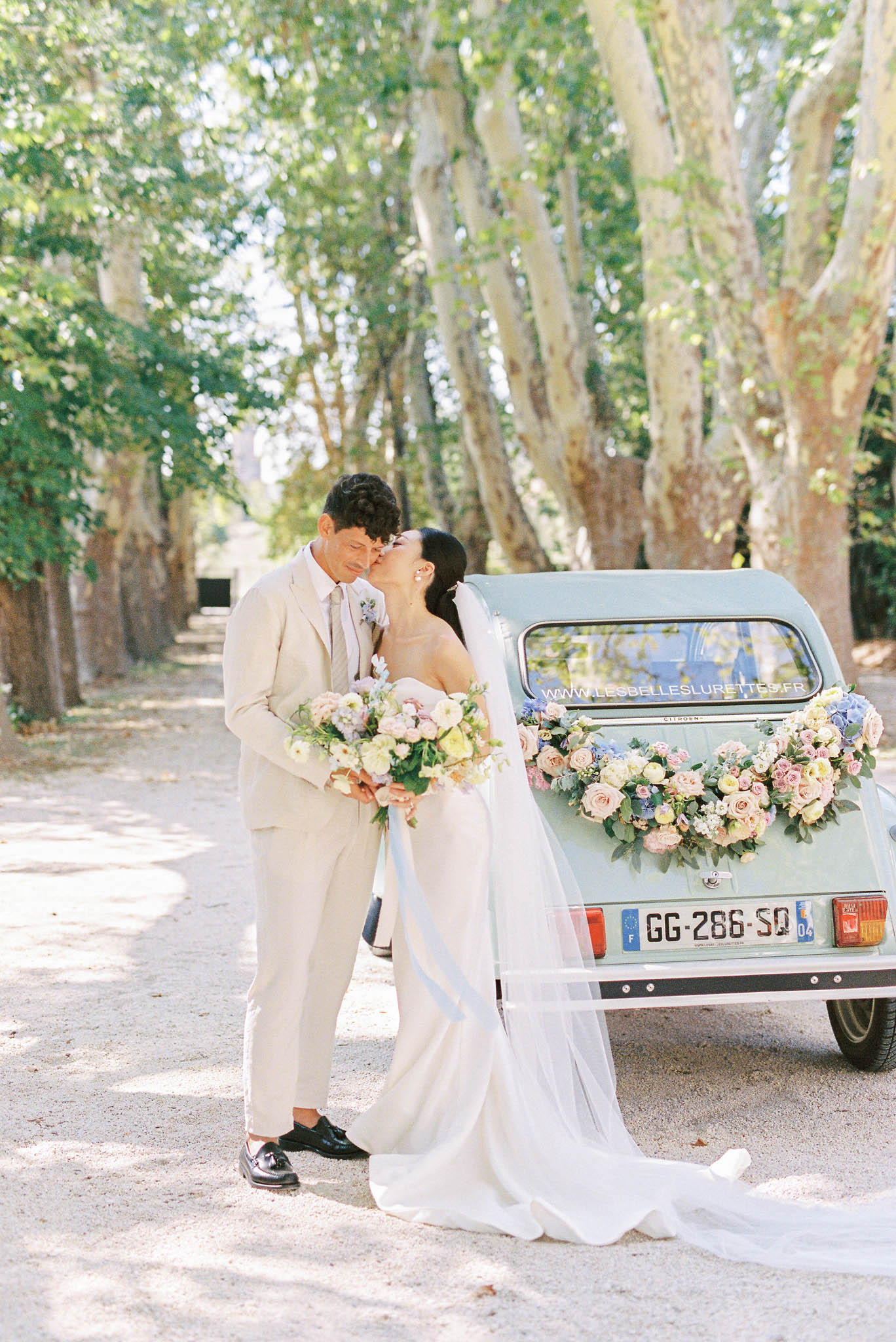 Couple kissing by mint-green Citroen 2CV with heart-shaped blush rose and blue hydrangea arrangement