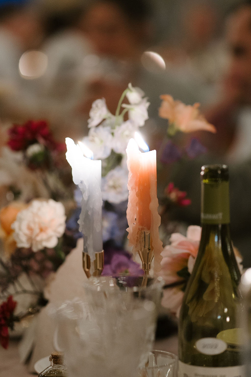 Wedding table centerpiece with gold candlesticks, blush peonies, deep red blooms, and garden-style floral arrangement