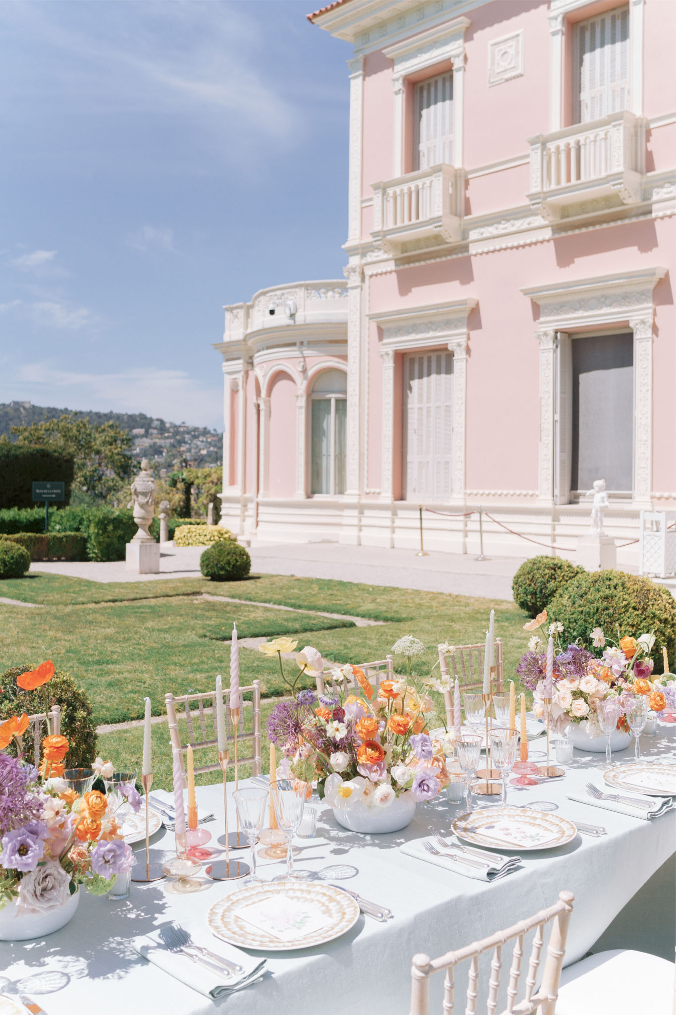 Wedding reception table at a pink Belle Epoque villa with colourful floral centrepieces and gold-rimmed plates
