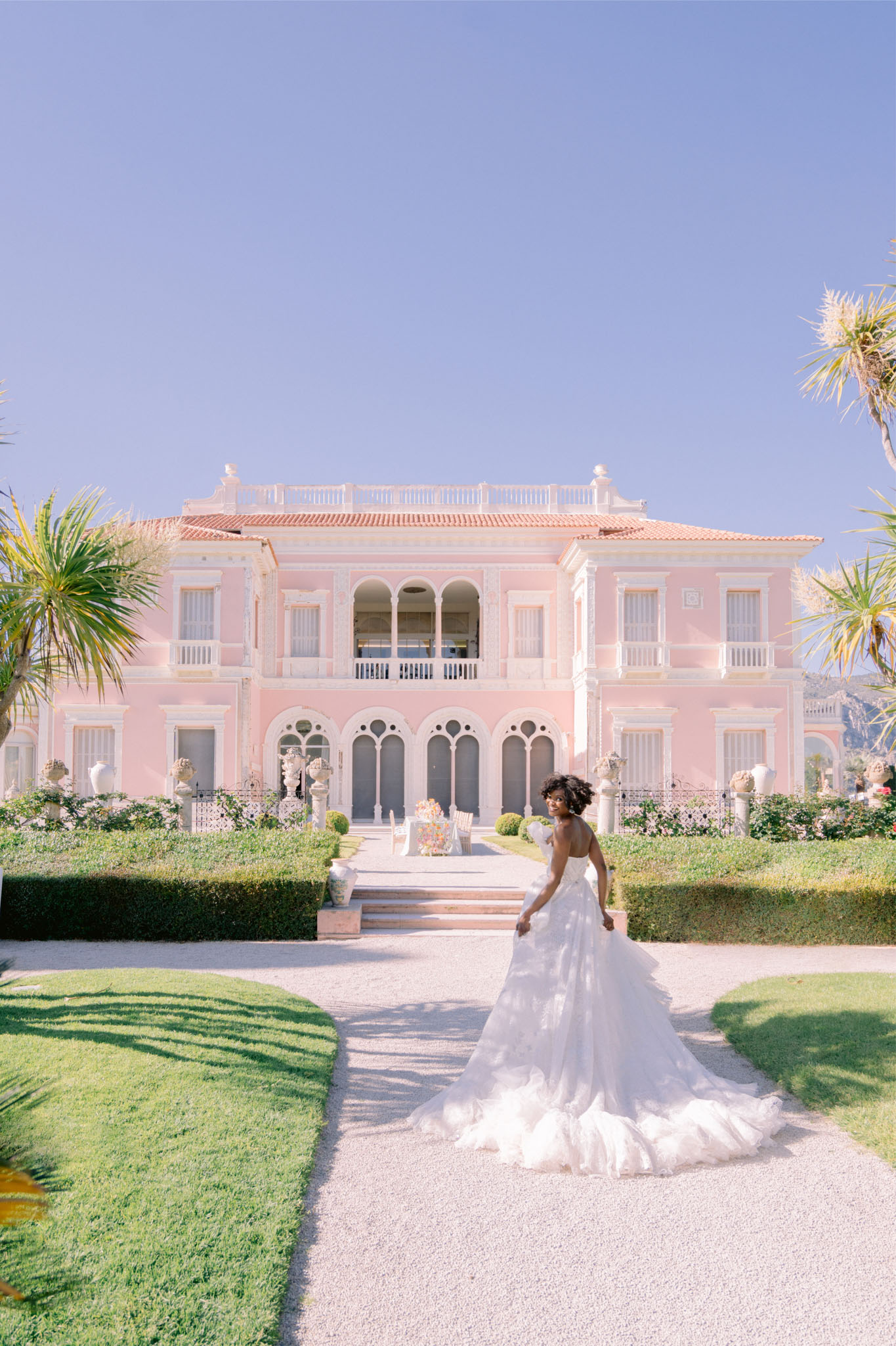 Bride in ruffled tulle ballgown with cathedral train on gravel path before Belle Epoque villa