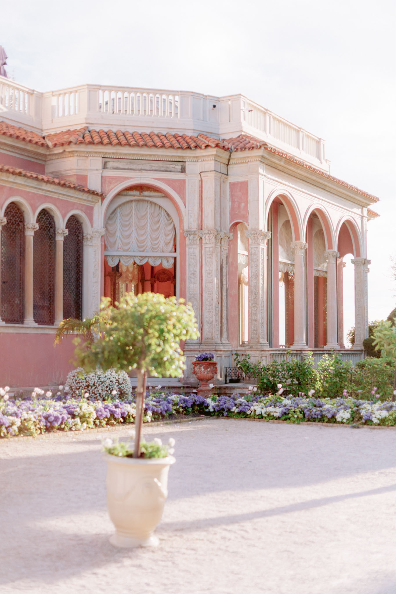 Villa Ephrussi with pink rendered walls, white columns, and hydrangea garden beds on the French Riviera