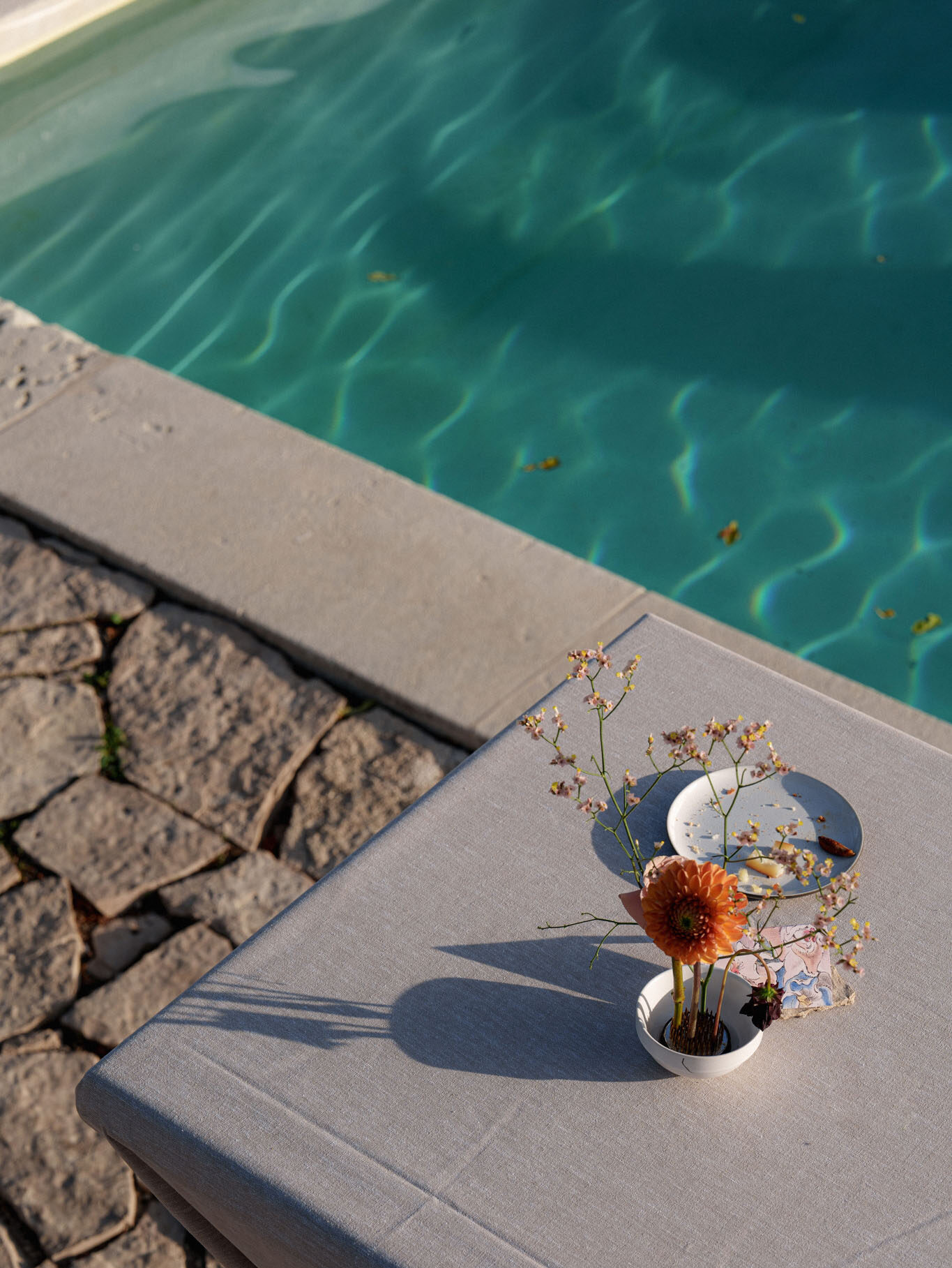 Small floral arrangement with orange gerbera and pink wax flowers on a poolside sun lounger