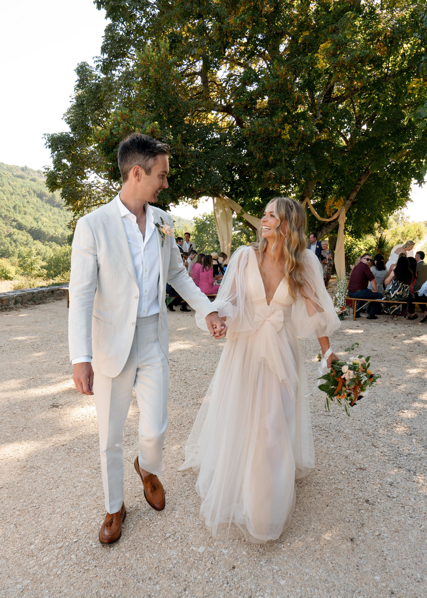 Bride and groom walking down the aisle after outdoor ceremony, bride in blush tulle gown with orange and peach bouquet