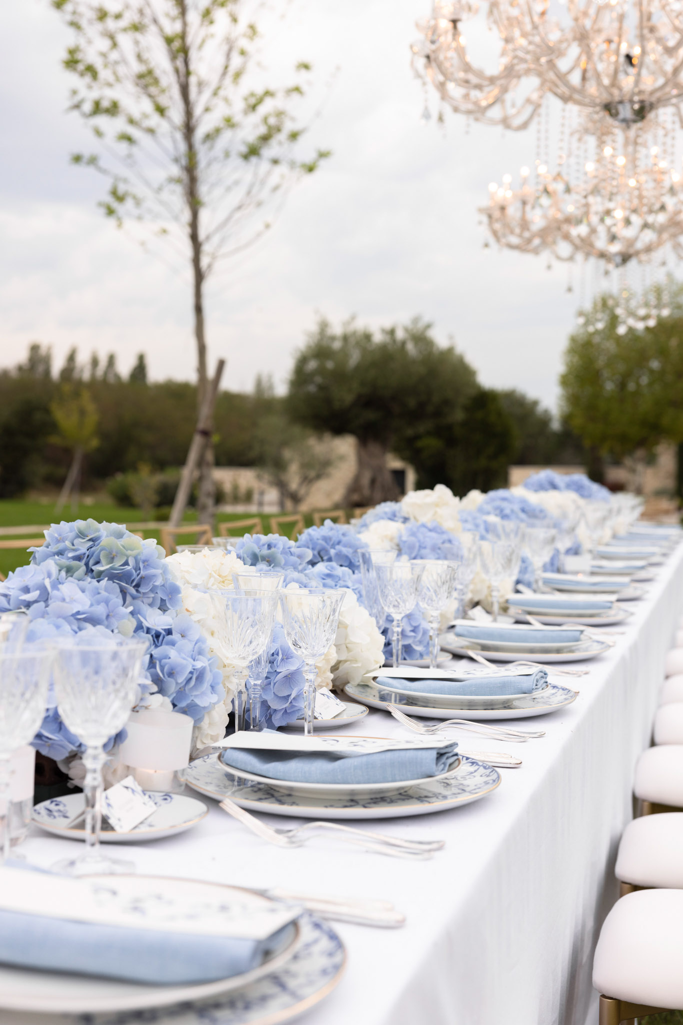 Garden reception table with blue-and-white floral china pale blue hydrangeas ivory roses crystal chandelier overhead
