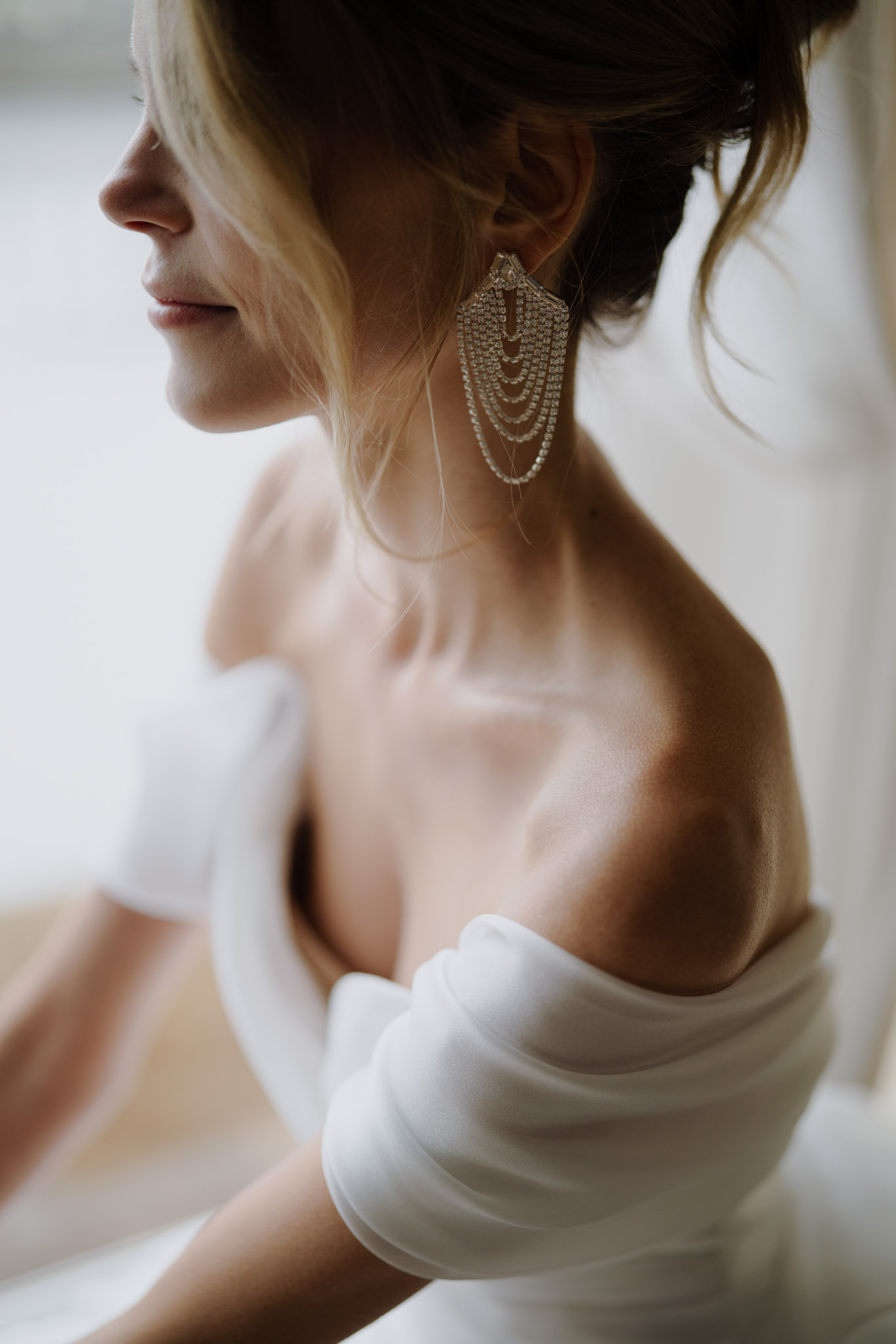 Close-up profile of bride wearing Art Deco crystal and pearl chandelier earring with off-shoulder gown