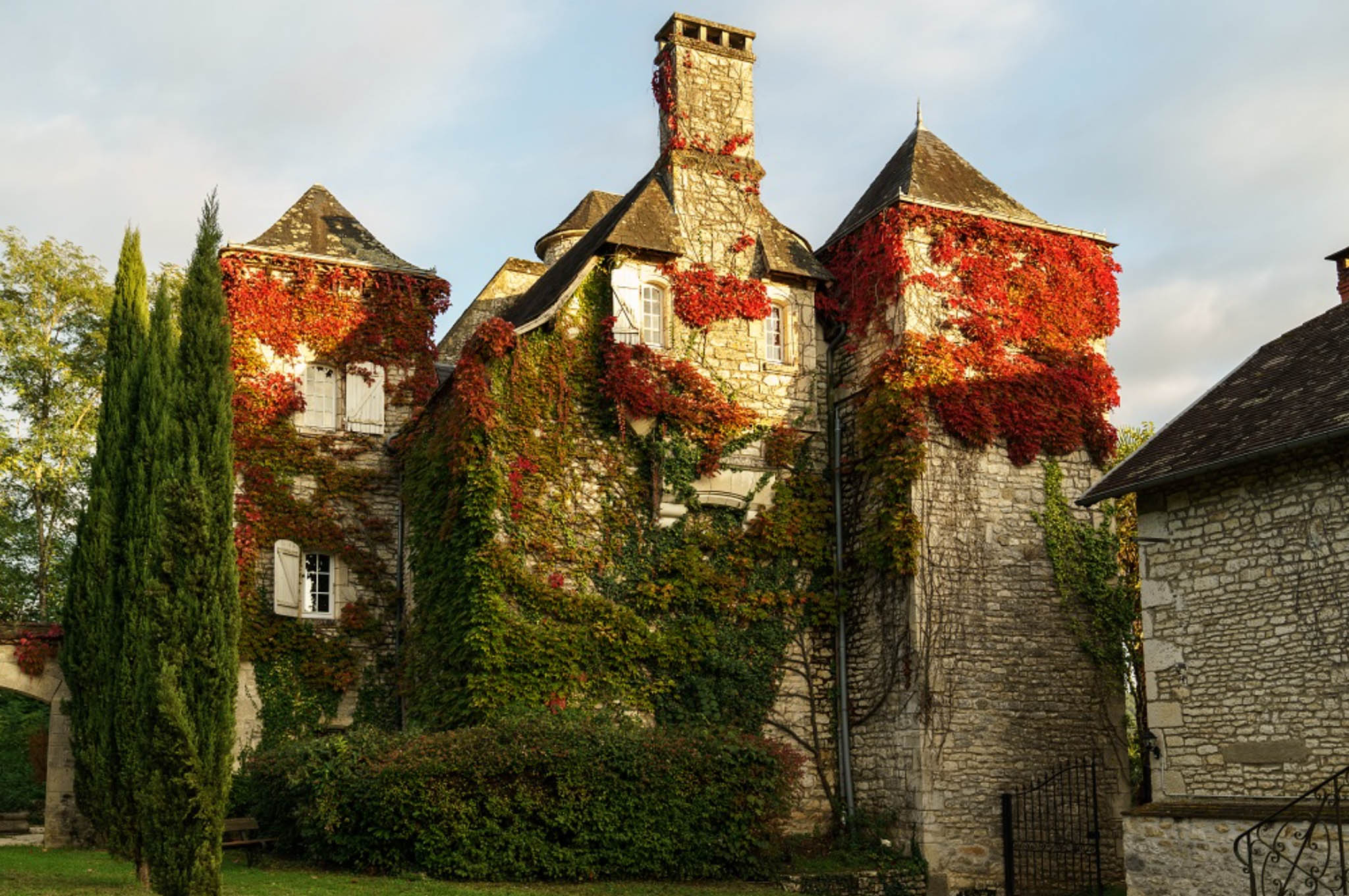 French stone manor with twin conical towers and climbing vines in red and green autumn foliage