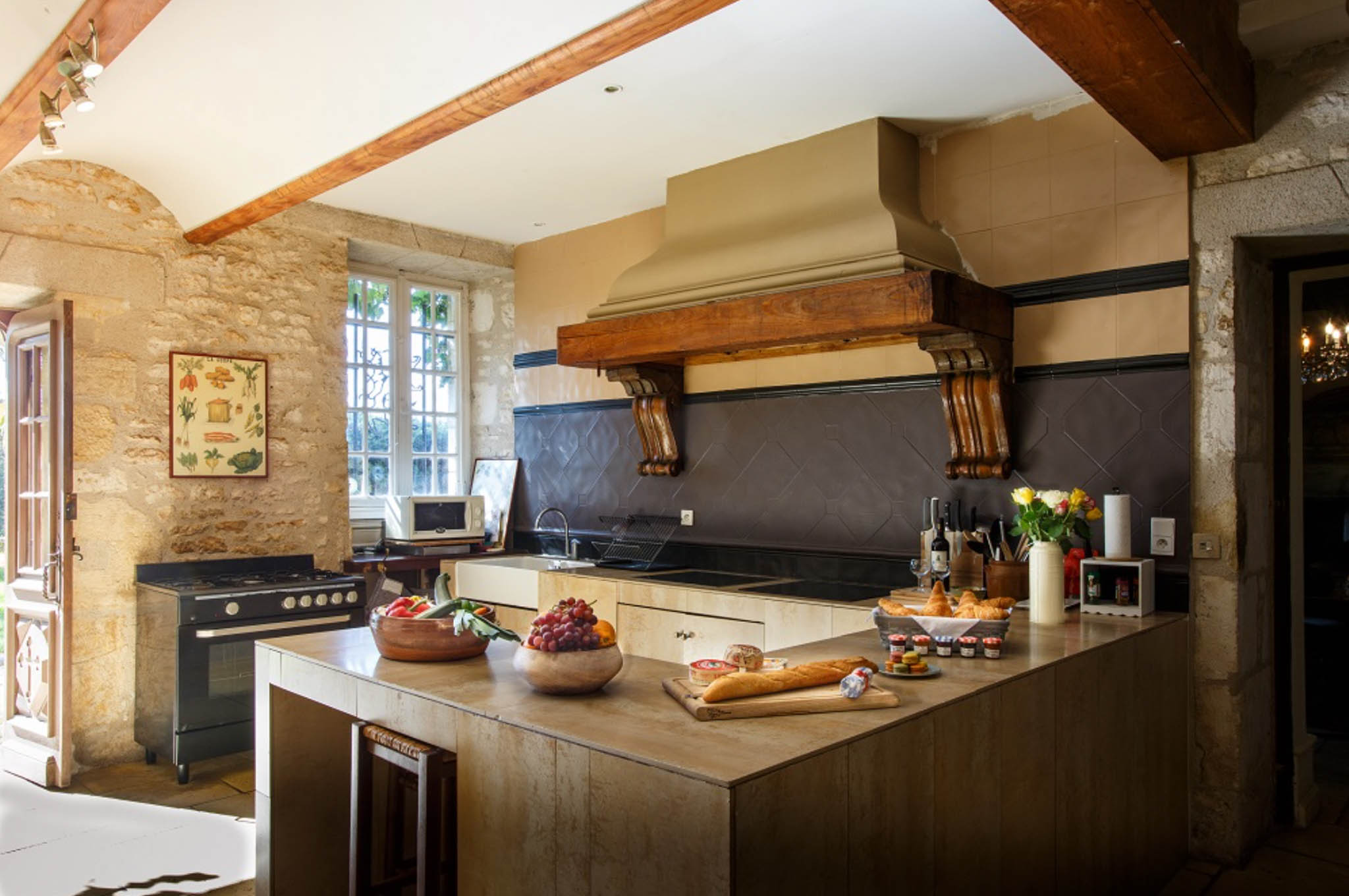Rustic French chateau kitchen with stone walls, wooden beams, and breakfast spread on stone-topped island
