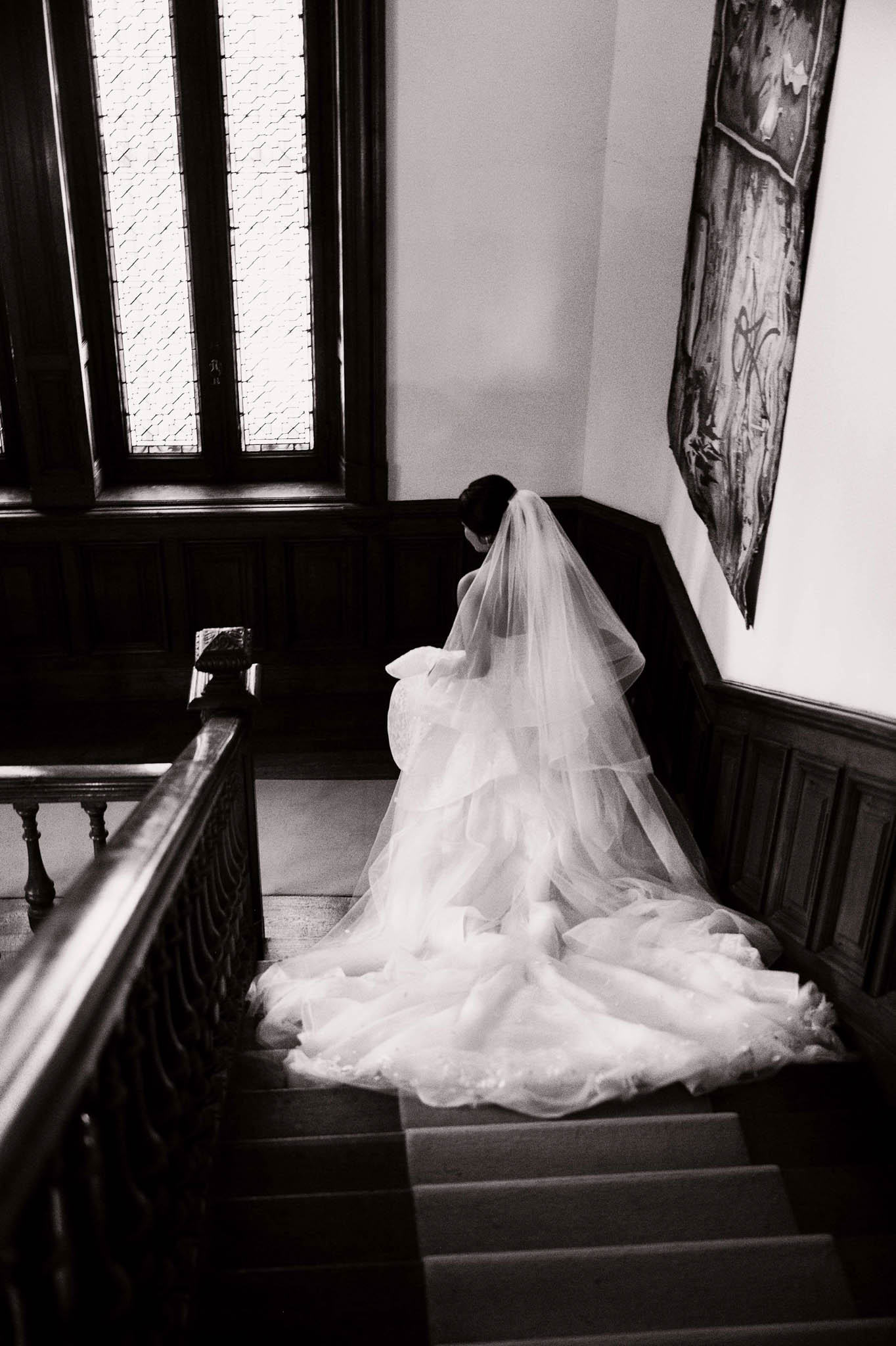 Black and white overhead bride on grand staircase with ball gown and cathedral tiered veil spread across steps