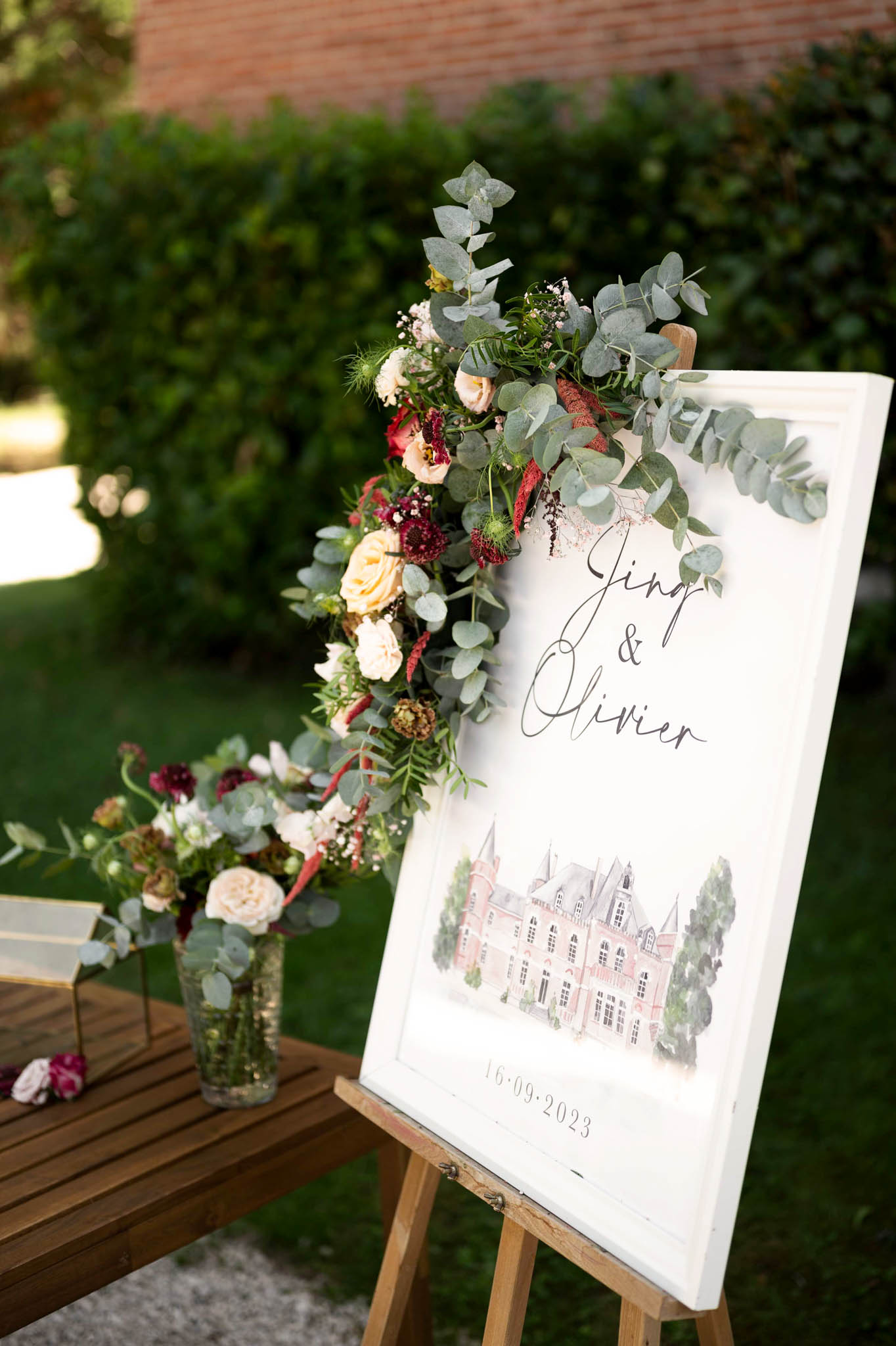 Welcome sign with watercolour chateau illustration and cascading burgundy dahlia and blush rose garland