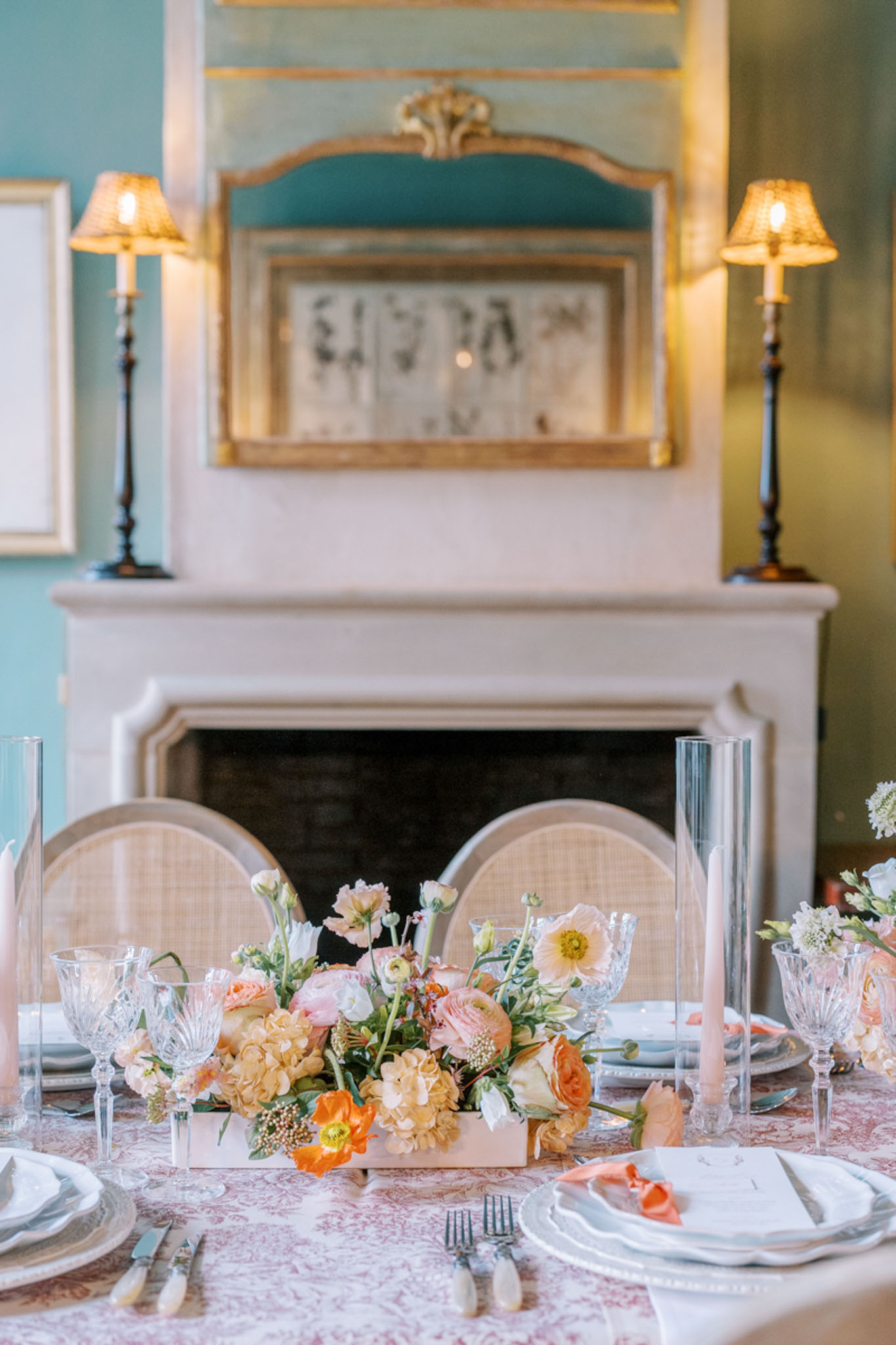 Round table styled with toile cloth, peach hydrangea and coral rose centerpiece, crystal stemware, and taper candles