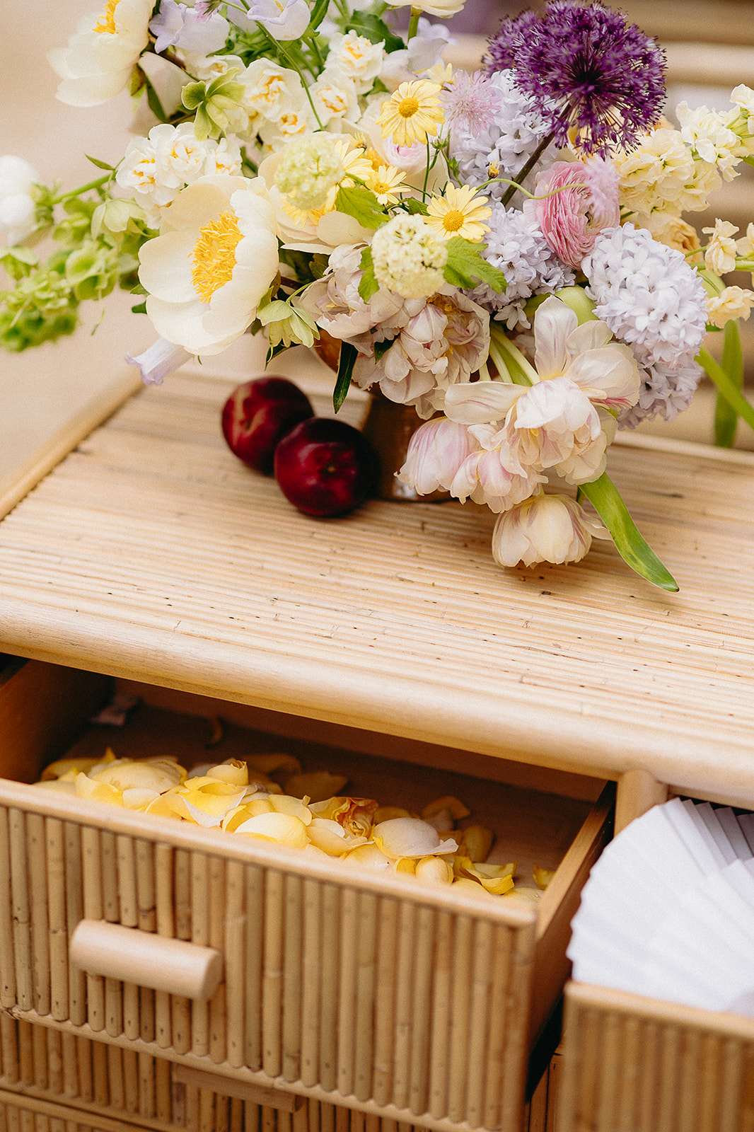 Rattan chest styling with parrot tulips, lavender hyacinths, and cream roses beside rose petal drawer
