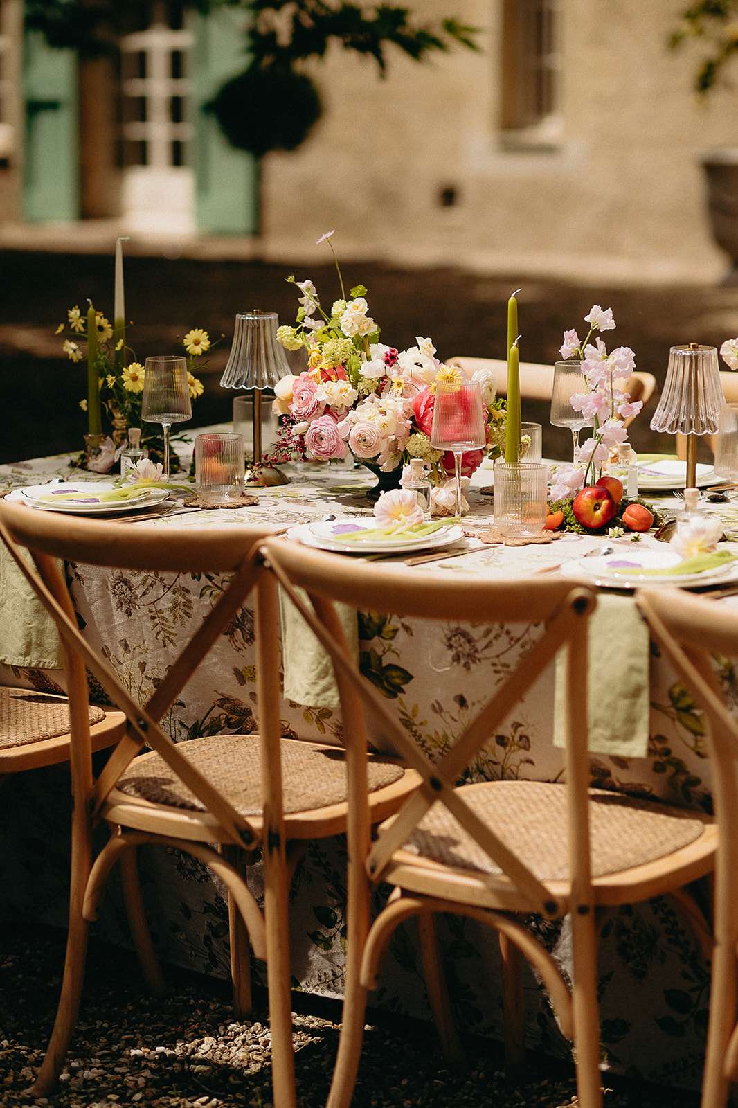 Botanical-print tablecloth with pink rose and anemone centrepiece, olive tapers, and apricot accents