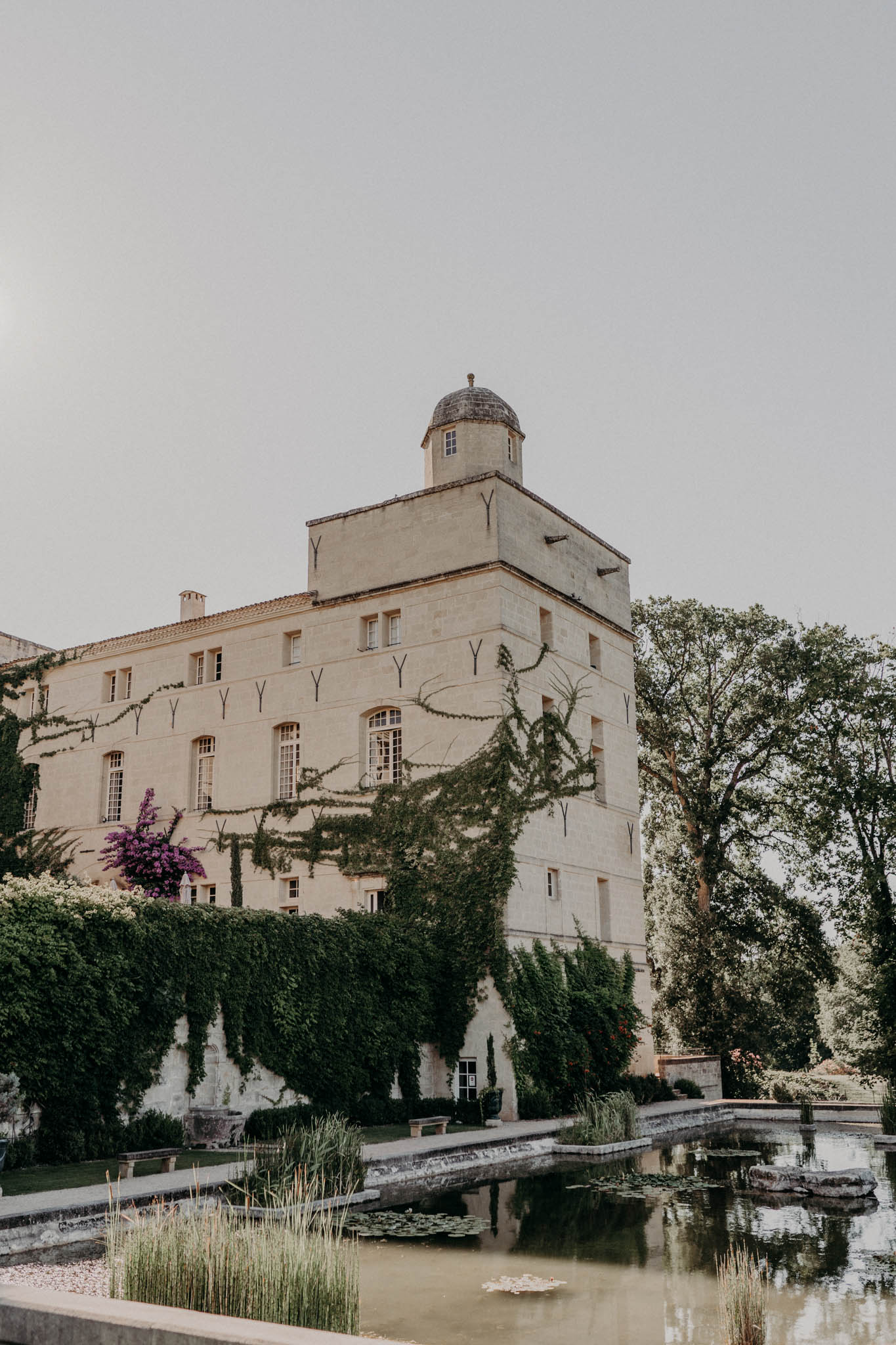 French chateau exterior with domed turret climbing ivy and formal reflecting pool with lily pads