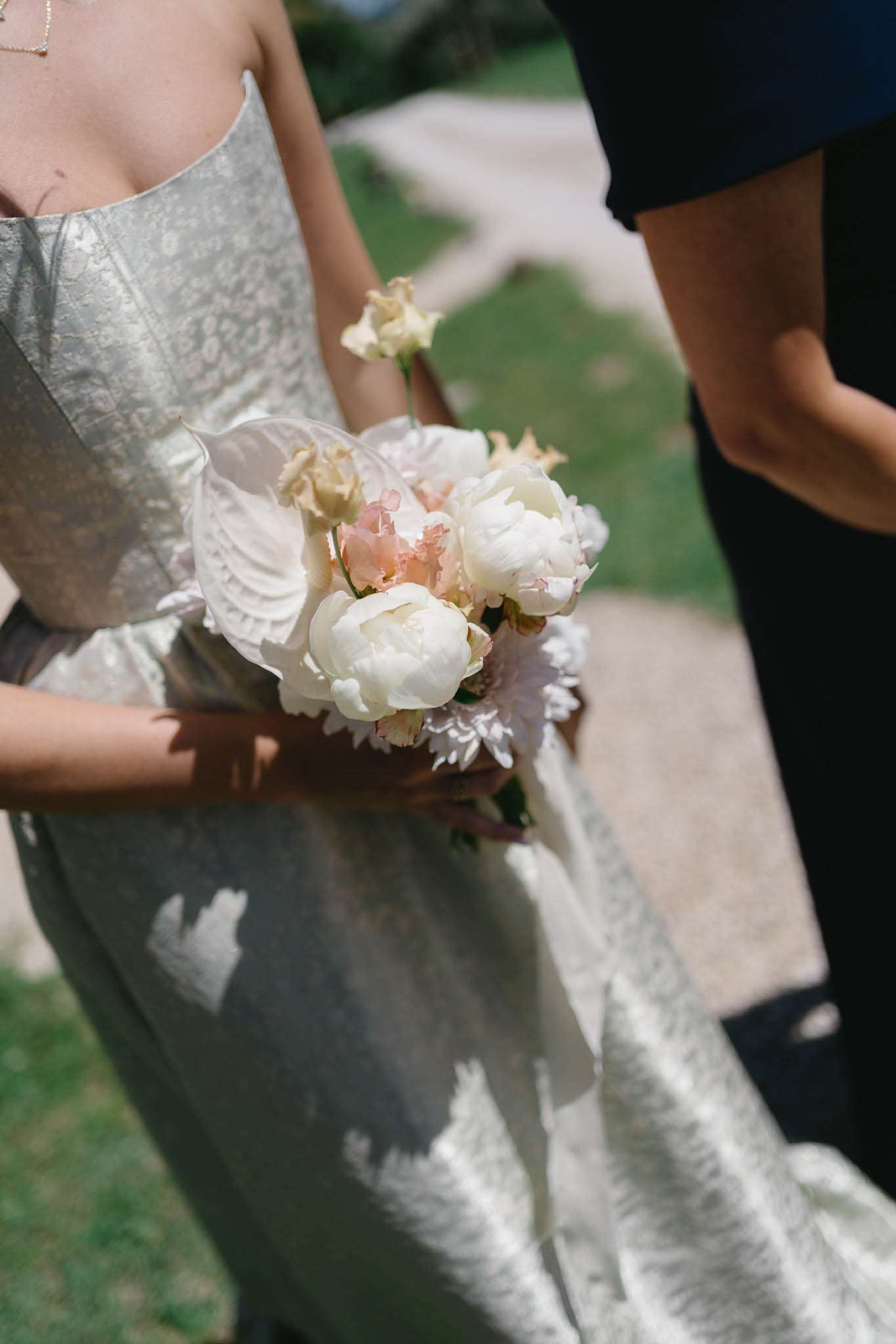 Bride holding compact bouquet of cream peonies, blush sweet peas, and white calla lilies