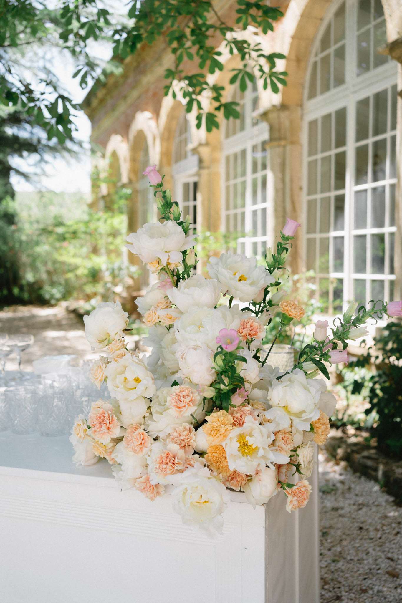 Garden-style floral arrangement with white peonies, peach carnations, and pink lisianthus on chateau terrace