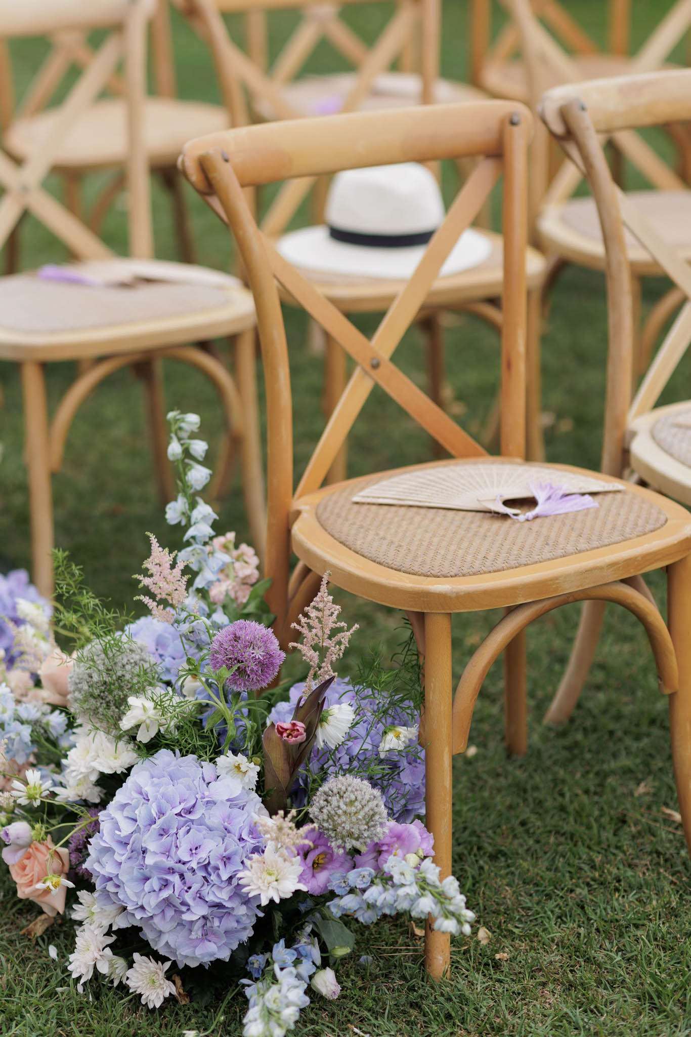 Ceremony aisle florals with lavender hydrangeas, purple alliums, and blush astilbe by crossback chairs
